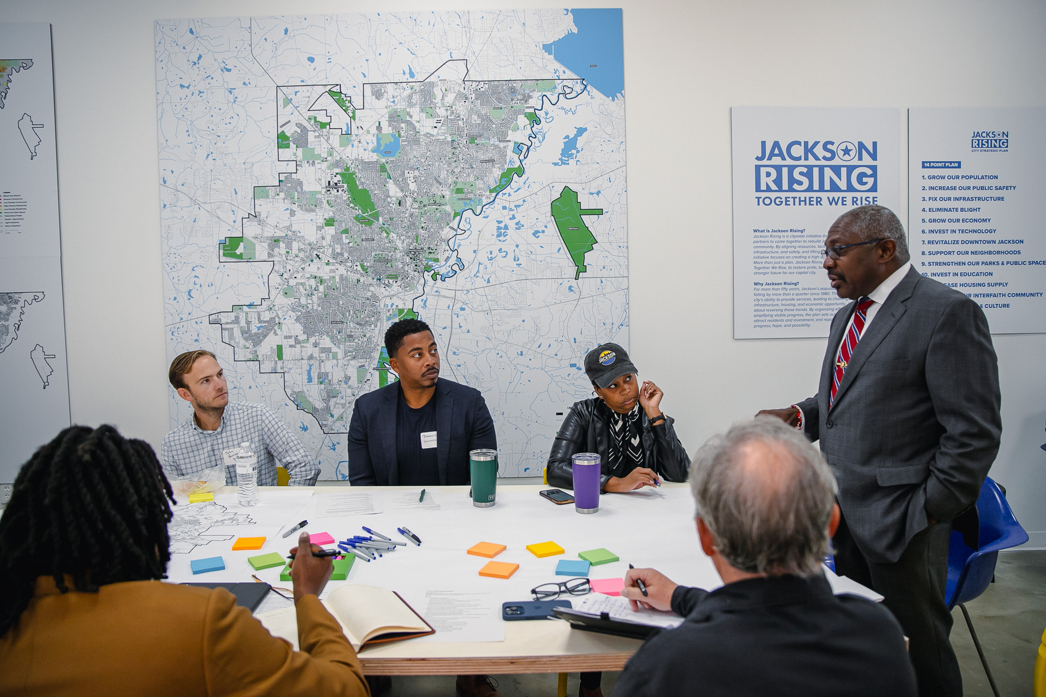 Mayor John Horhn addressing community leaders at a Jackson Rising workshop, with the city map and 14-point plan board behind